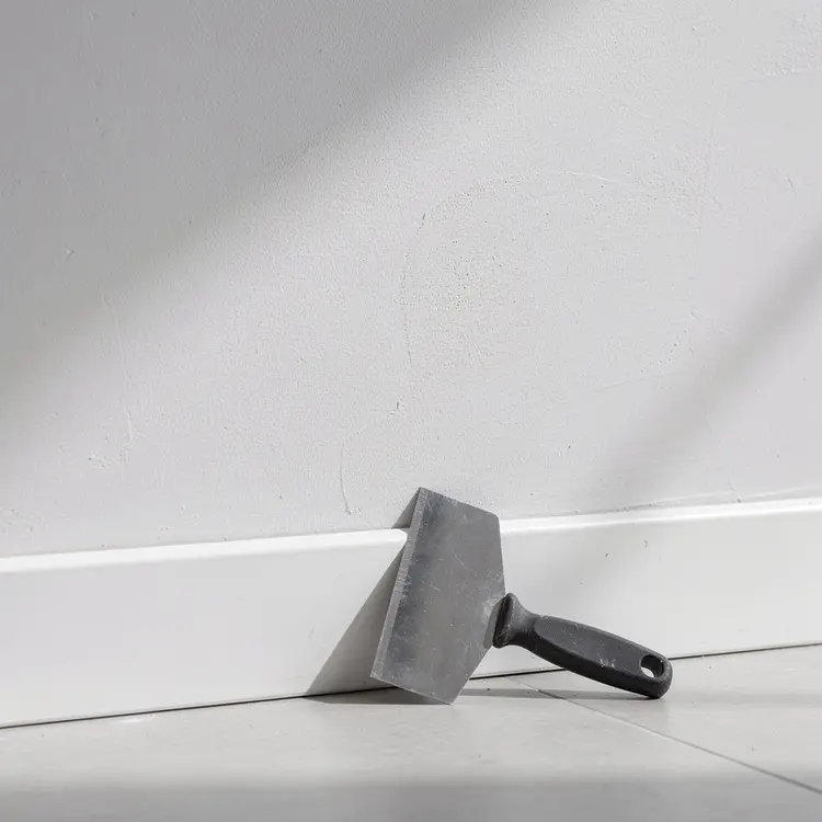 Drywall Taping Knife Against Freshly Plastered Wall