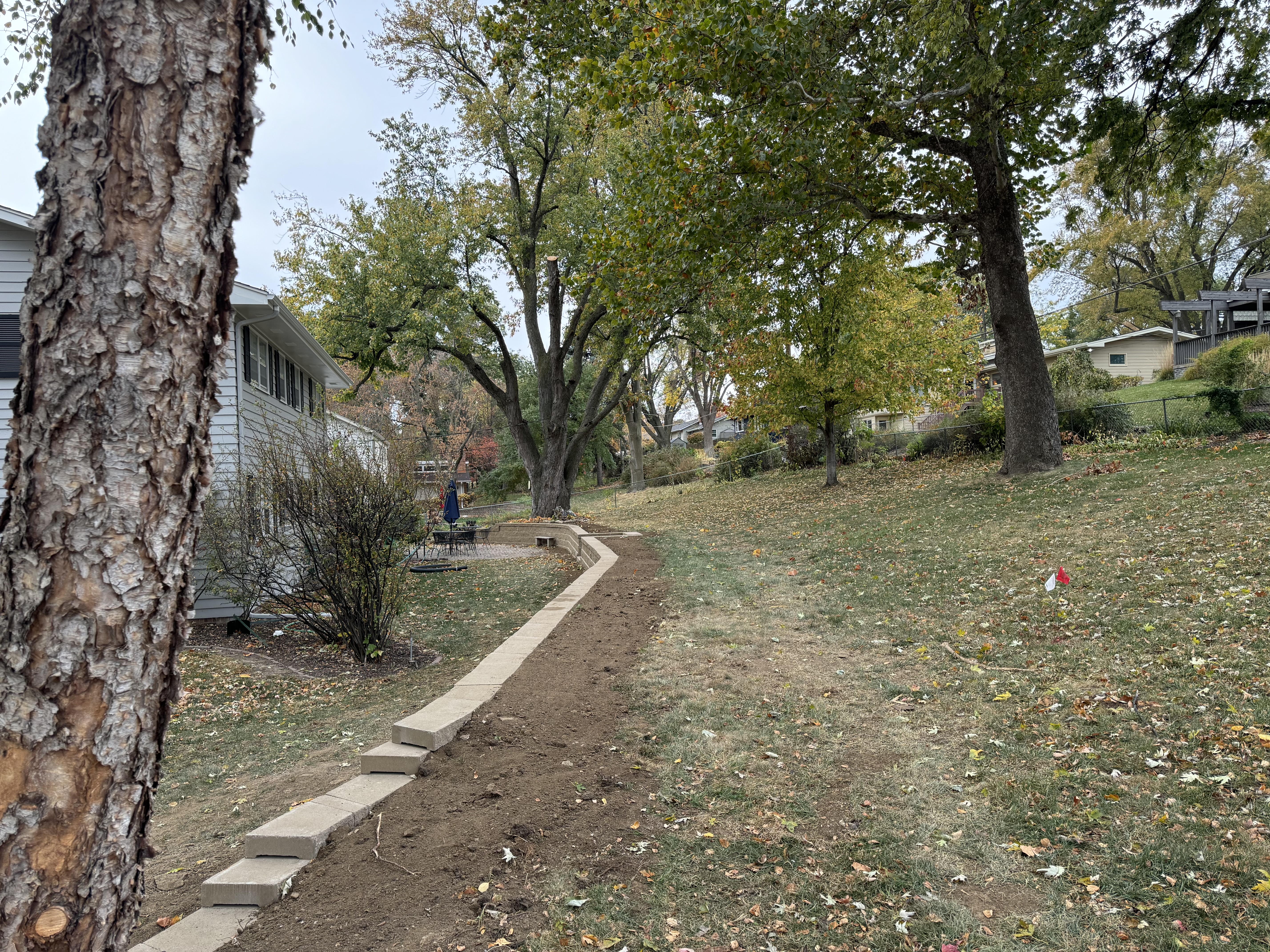 Block Retaining Wall Installation Along Sloped Yard