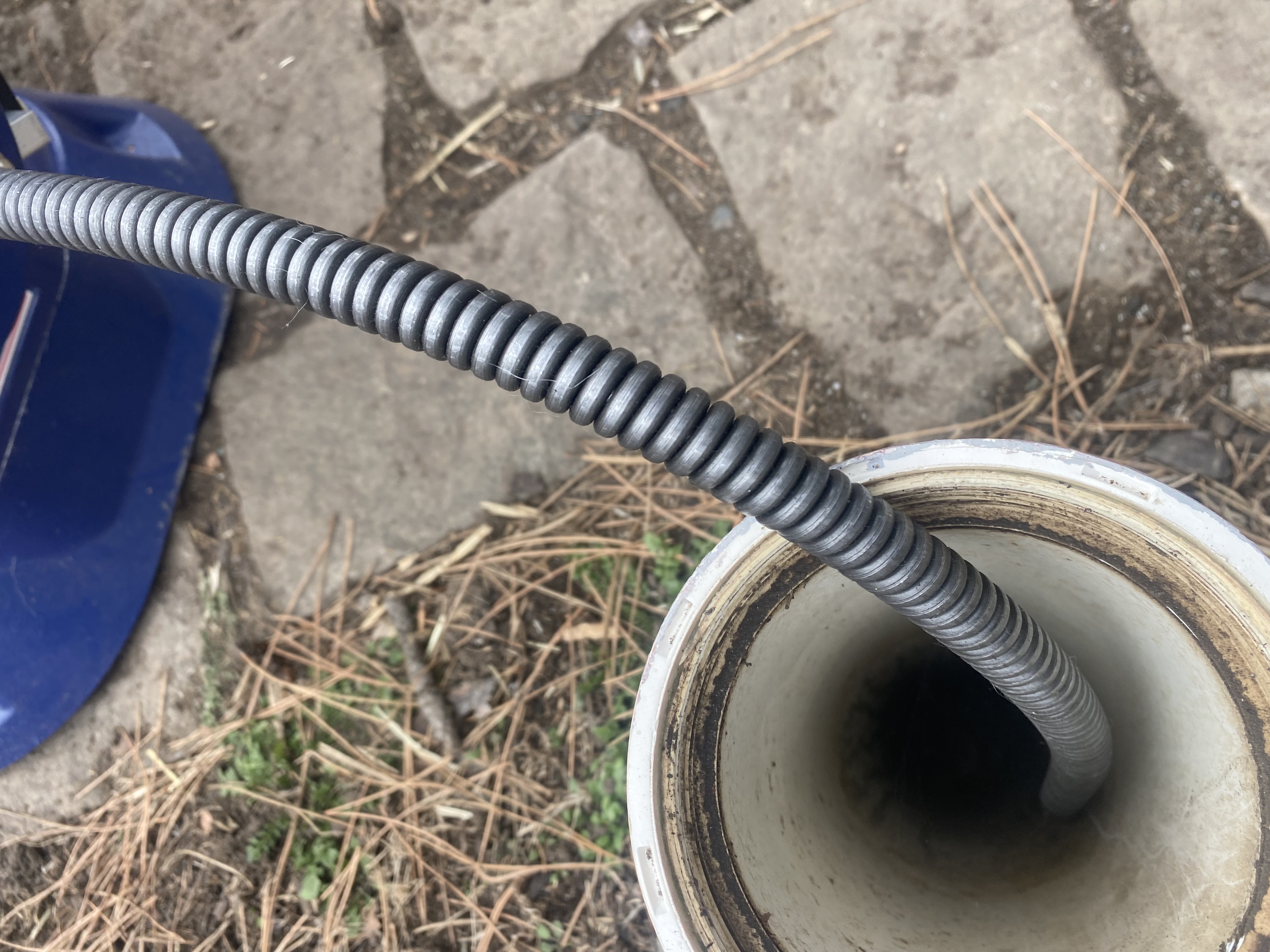 Drain Snake Being Fed Into Outdoor Drain Pipe